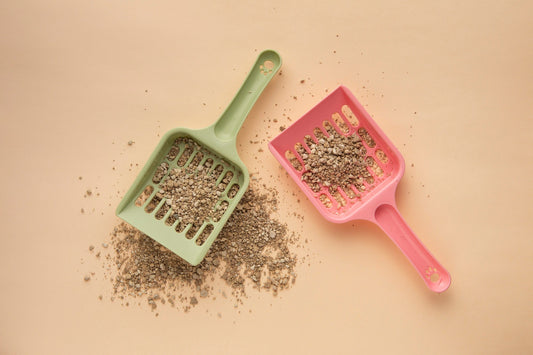 two cat litter shovels with beige background