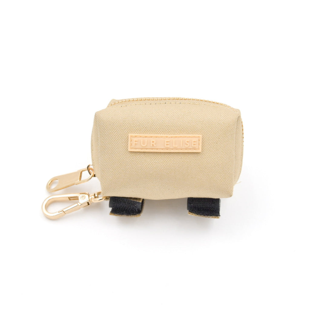 Beige pouch with black accents and a gold tag on a white background