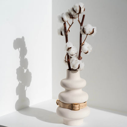 White vase with cotton branches on a white surface