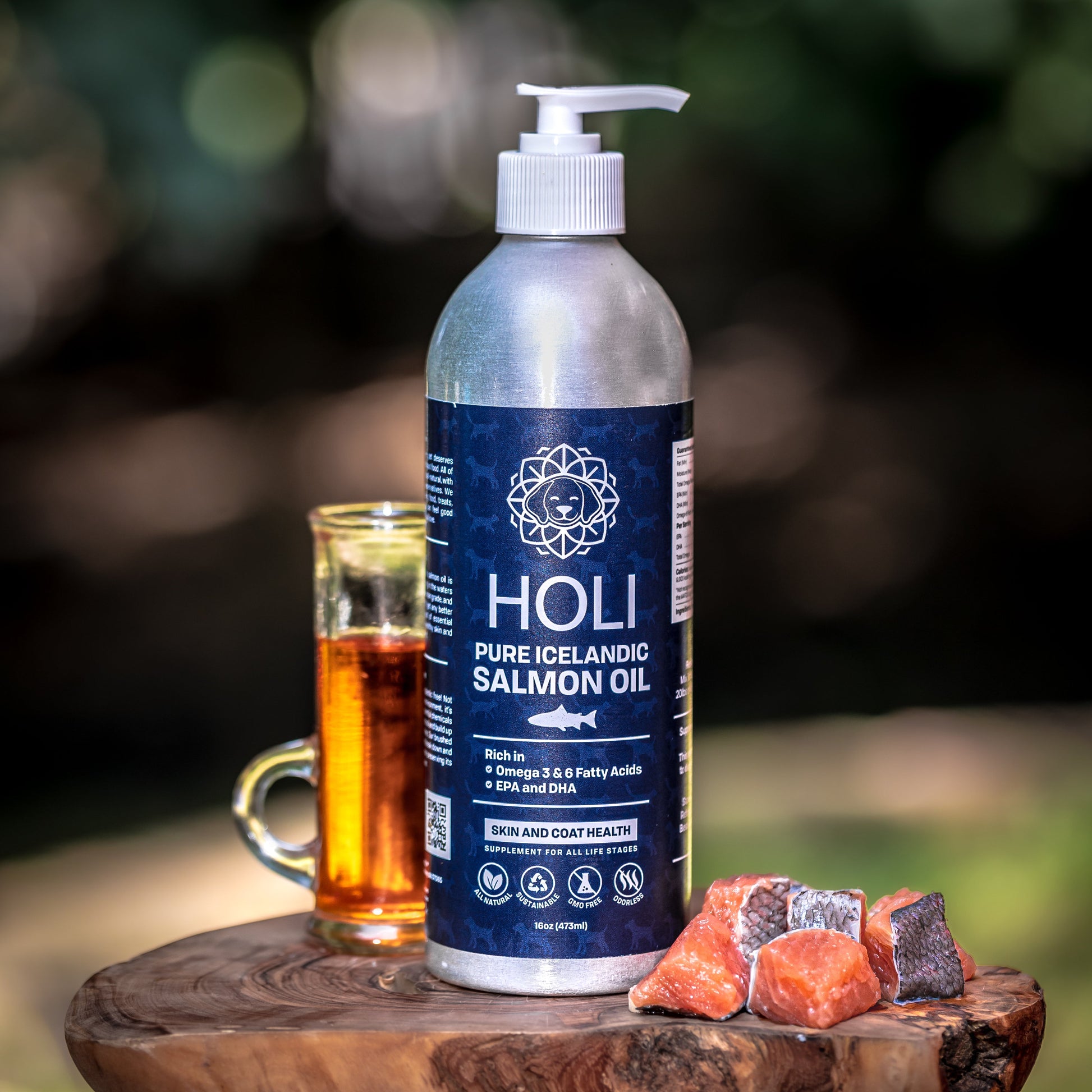 Bottle of Holi Pure Icelandic Salmon Oil with a glass of fish oil and salmon pieces on a wooden surface.