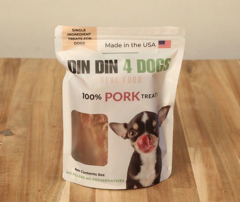 Package of 'Din Din 4 Dogs' pork treats for dogs on a wooden surface