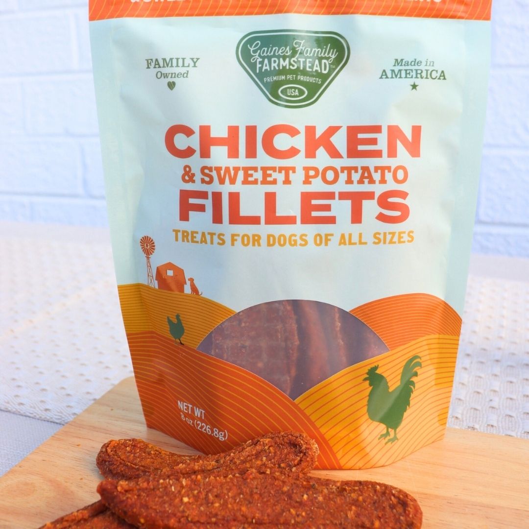 Bag of Gaines Family Farmstead Chicken & Sweet Potato Fillets treats for dogs on a wooden surface.