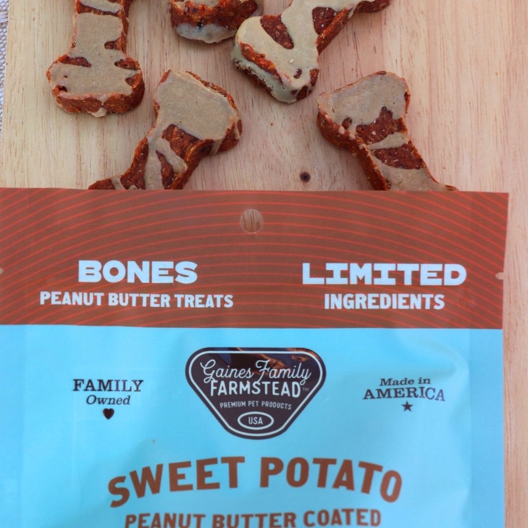 Gaines Family Farmstead sweet potato peanut butter coated treats on a wooden surface with packaging in the foreground.