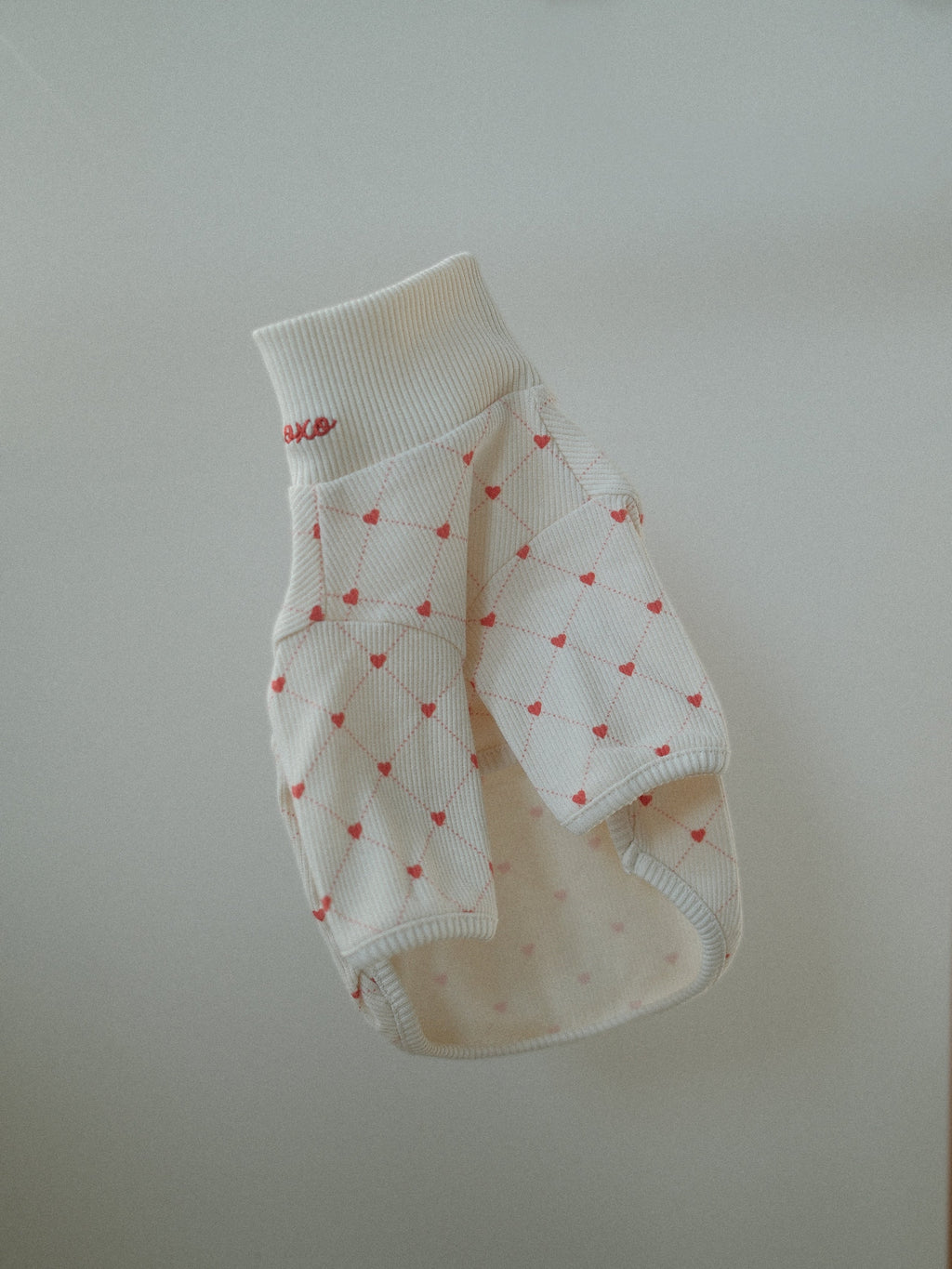 White pet sweater with red heart patterns on a light gray background