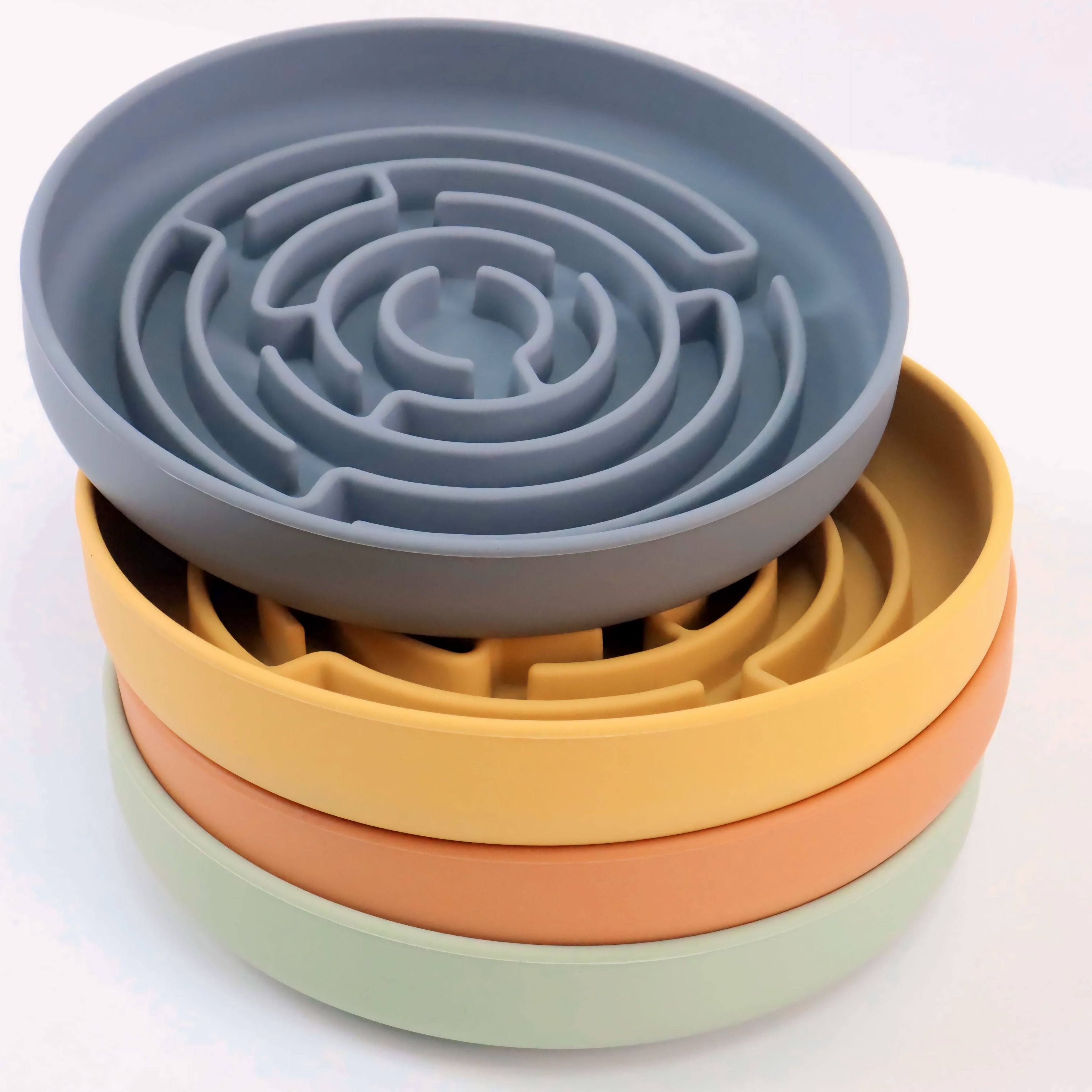 Stack of three silicone bowls with maze designs on a white background