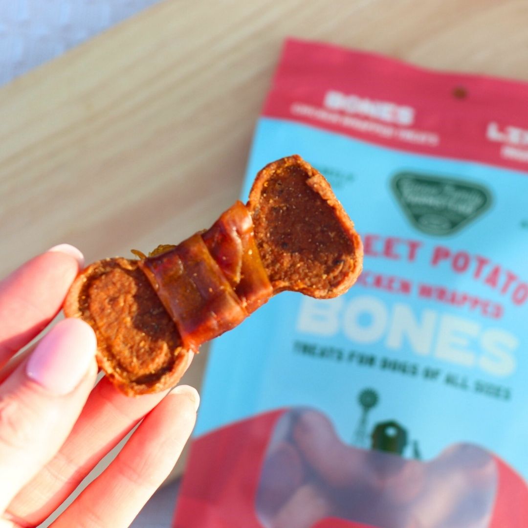 Dog treat shaped like a bone held in front of its packaging