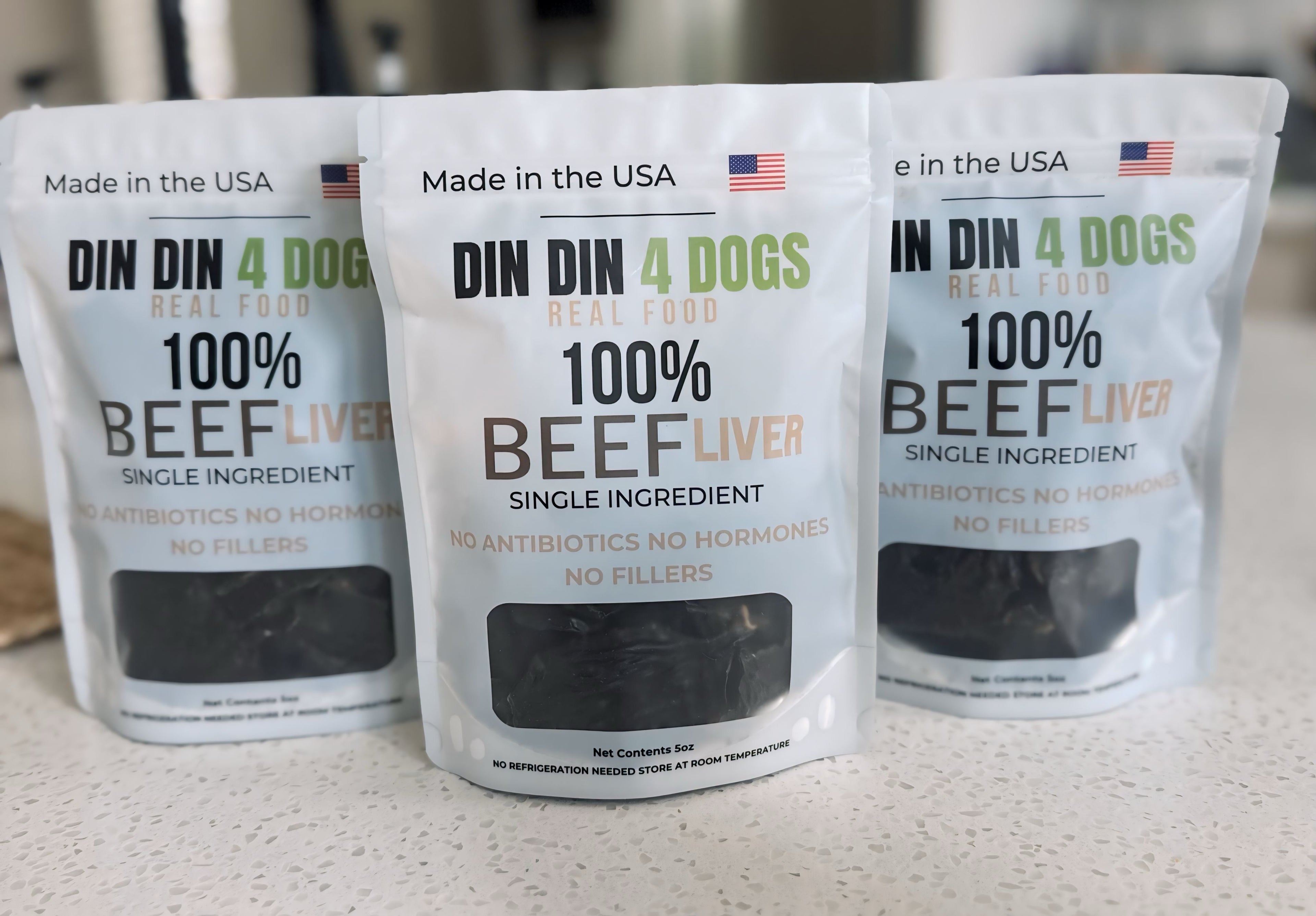 Three packages of DIN 4 Dogs 100% Beef Liver dog food on a light surface.