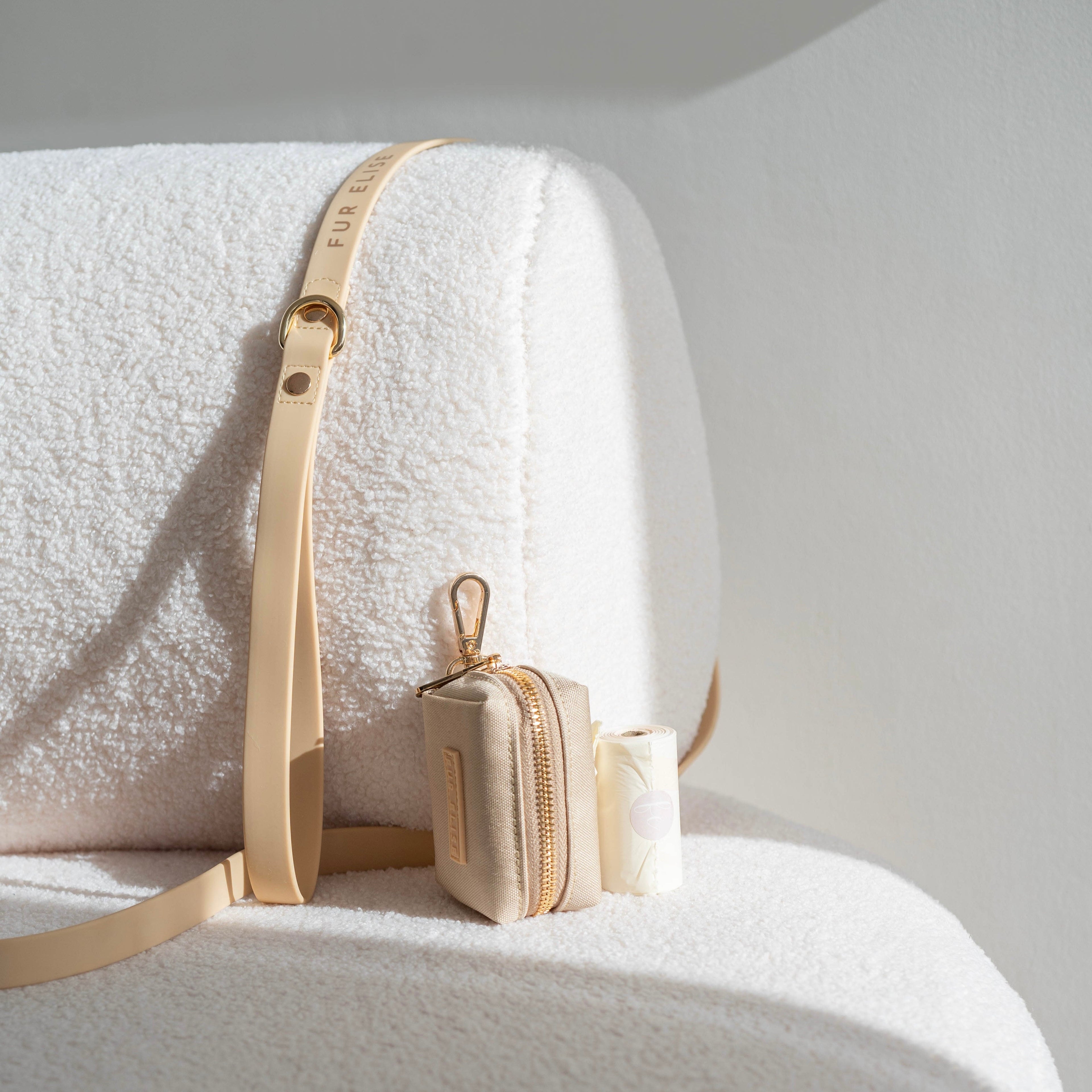 Gold belt and small pouch on a white surface with a neutral background