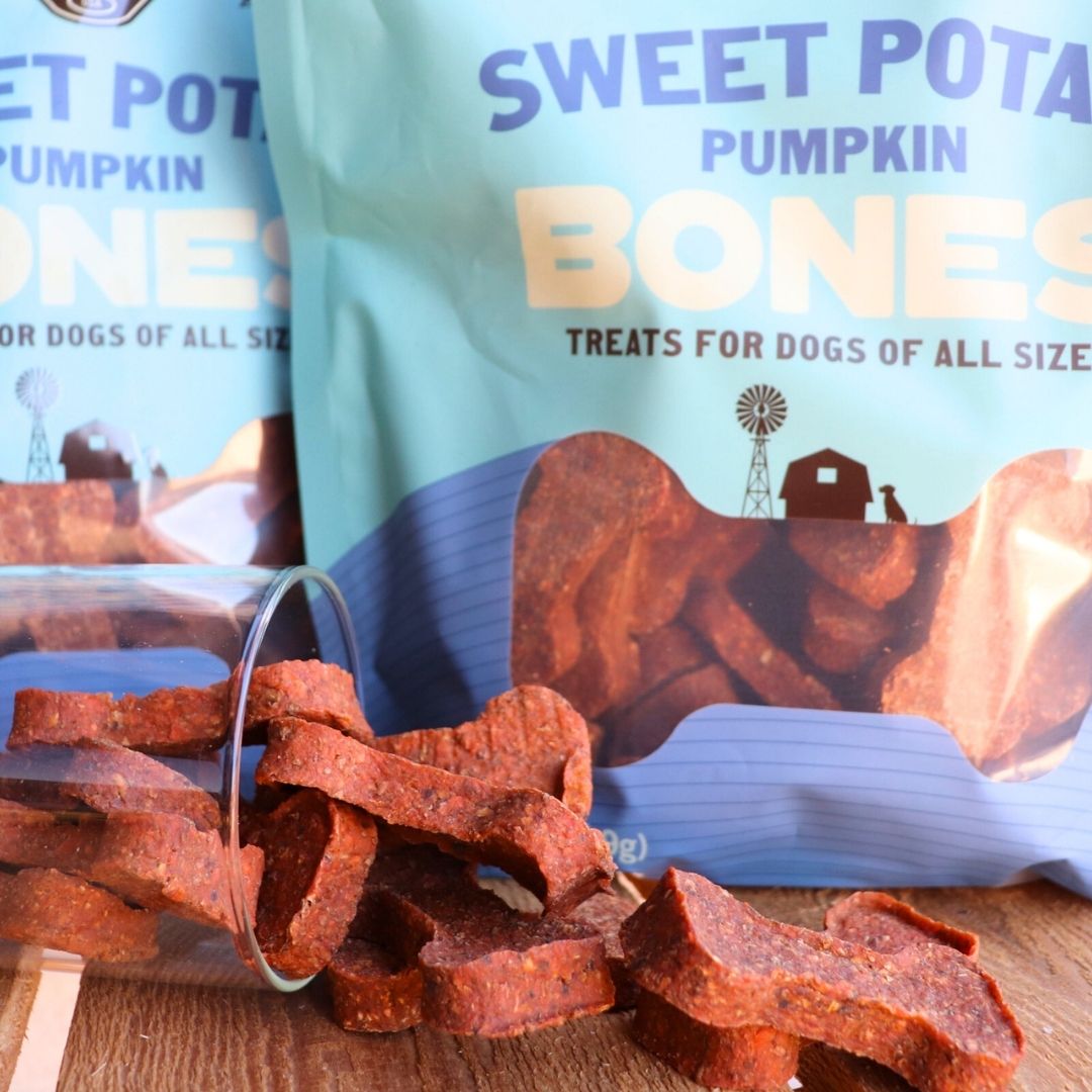 Sweet Potato Pumpkin Bones dog treats with packaging on a wooden surface