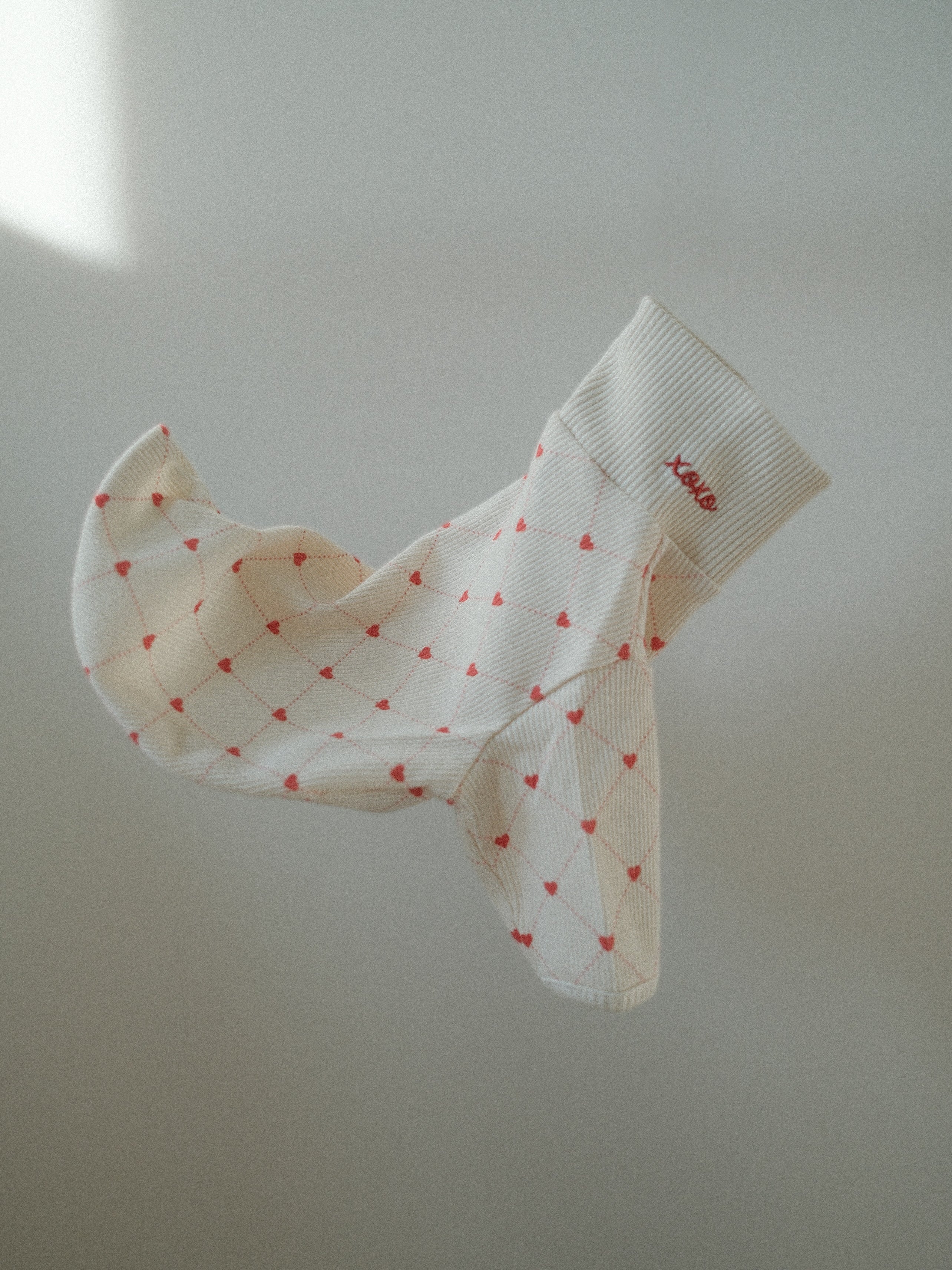 White pet sweater with red heart patterns on a light background