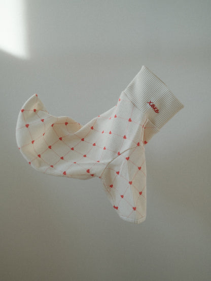 White pet sweater with red heart patterns on a light background