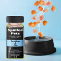 Spoiled Pets hydration enhancer bottle with salmon pieces falling into a bowl of water on a blue background