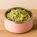 Pink pet bowl filled with food on a wooden surface