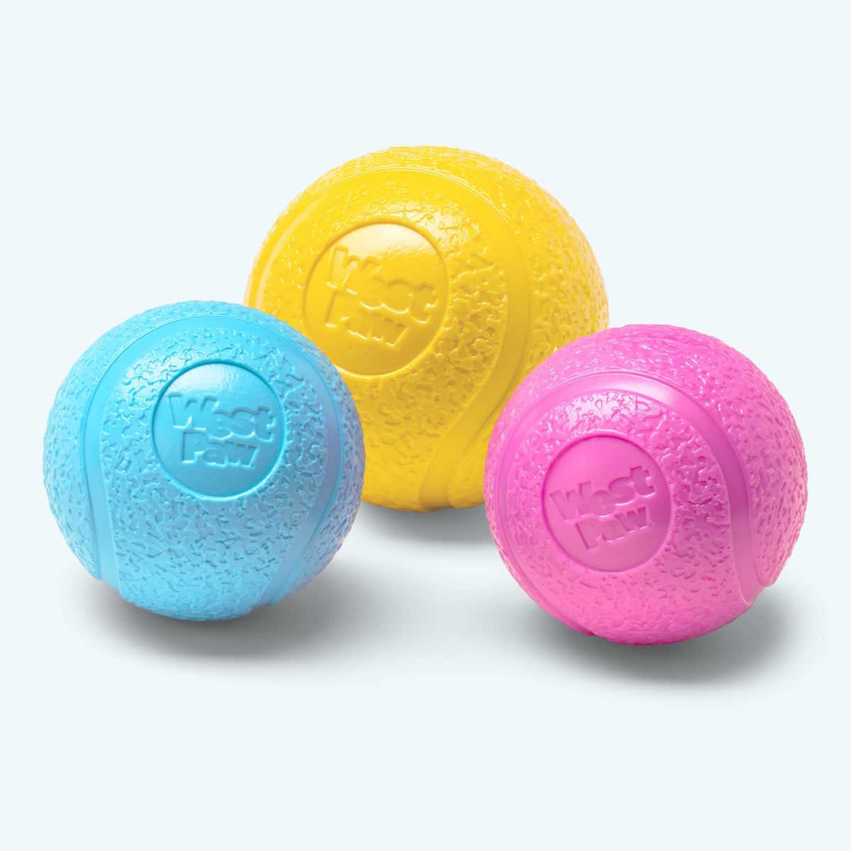 Three colorful rubber balls (yellow, blue, pink) on a light gray background