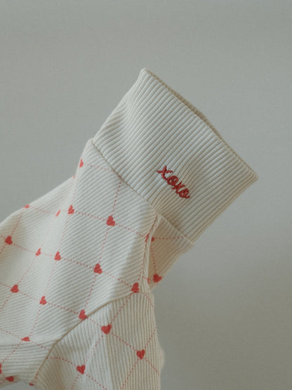 White dog sweater red heart patterns and 'XOXO' text on a light gray background