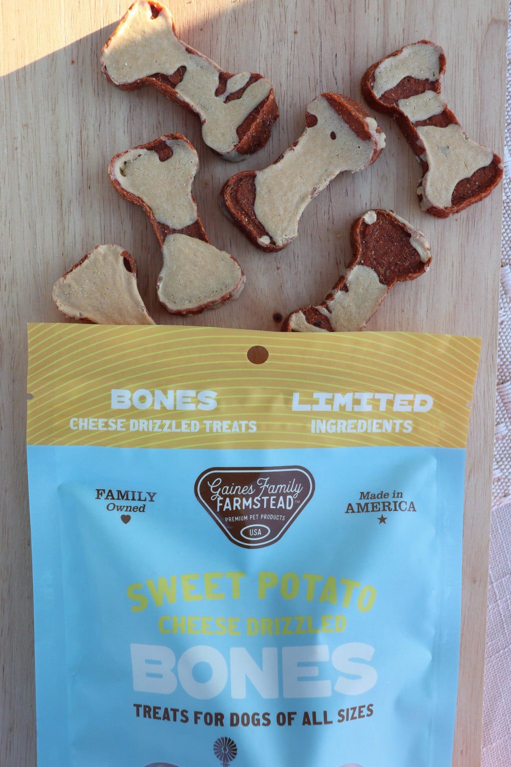 Bag of 'Sweet Potato Cheese Drizzled' dog treats with treats on a wooden surface