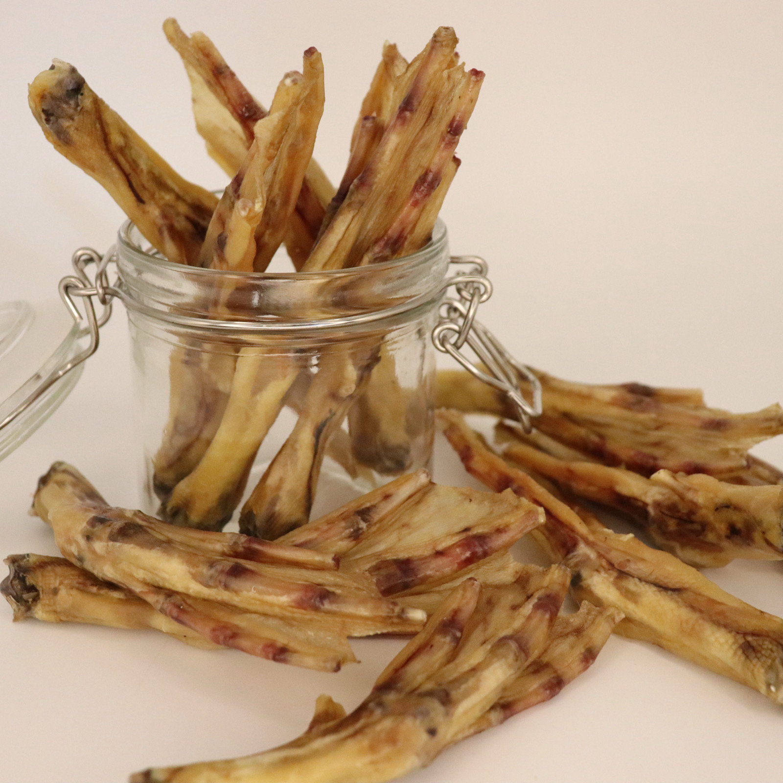 Dried duck feet in a glass jar on a white background