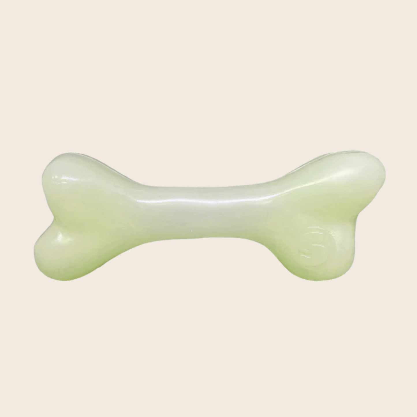 Green jade bone-shaped object on a beige background