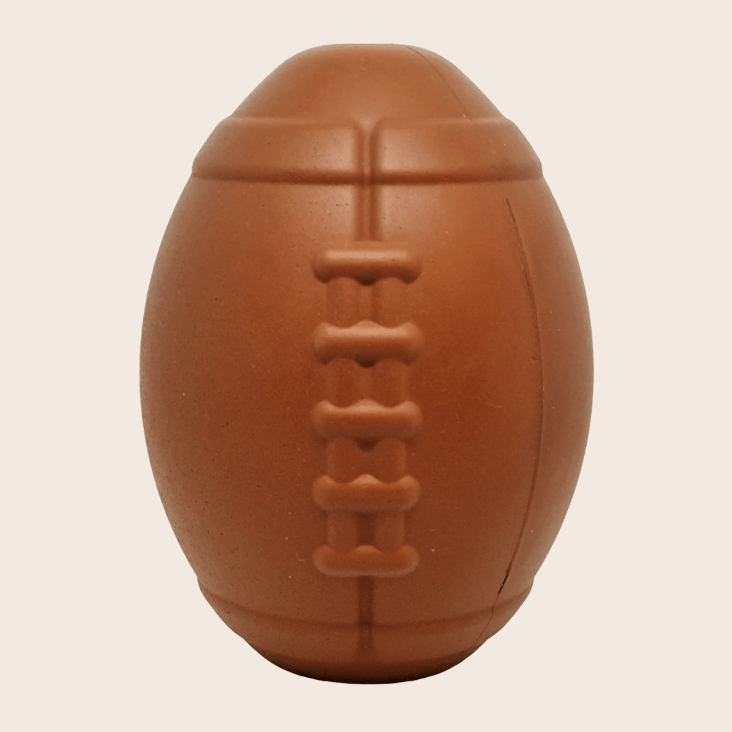 Brown dog toy shaped like a football on a beige background
