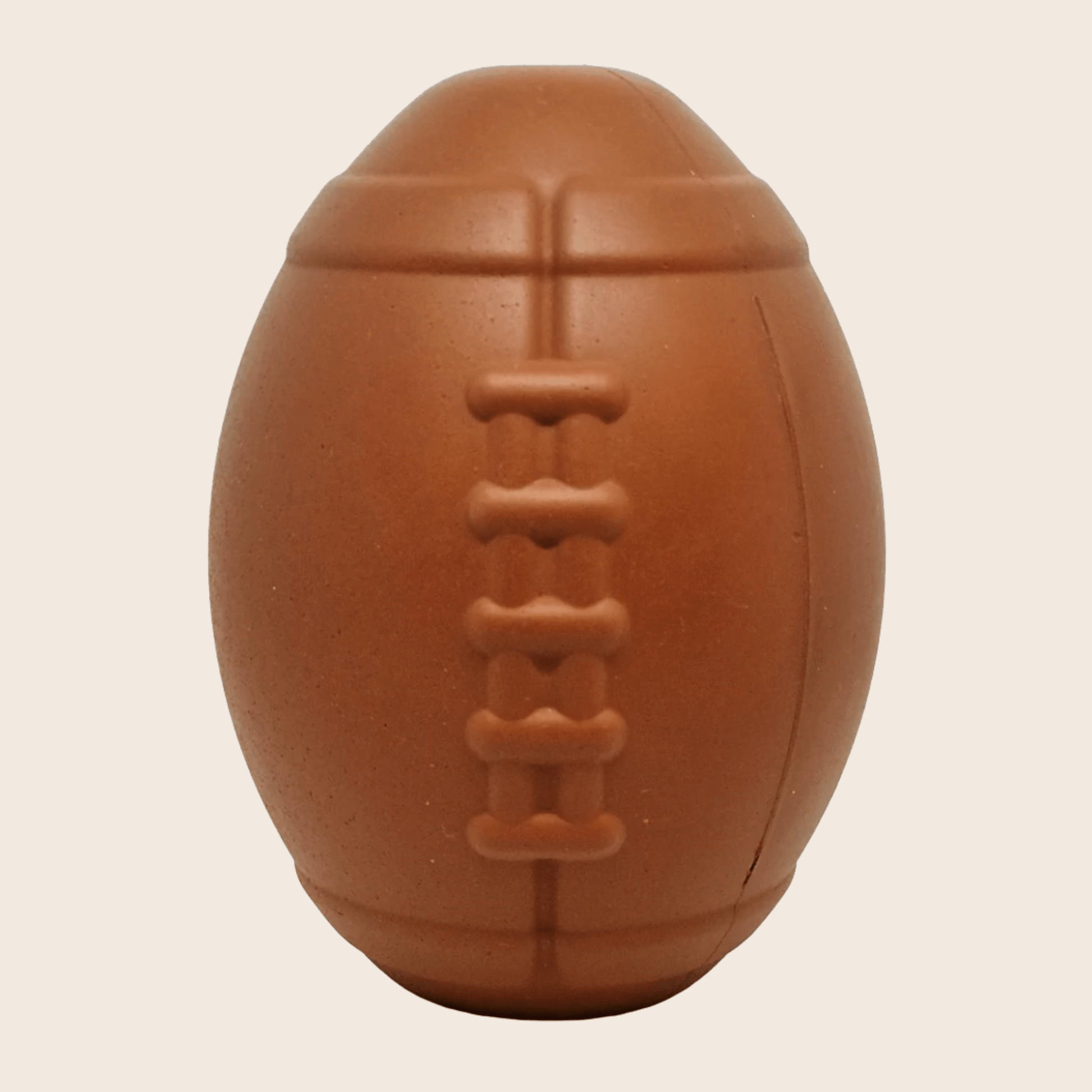 Brown dog toy shaped like a football on a beige background