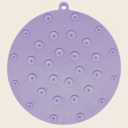 Purple silicone mat with suction cups on a beige background