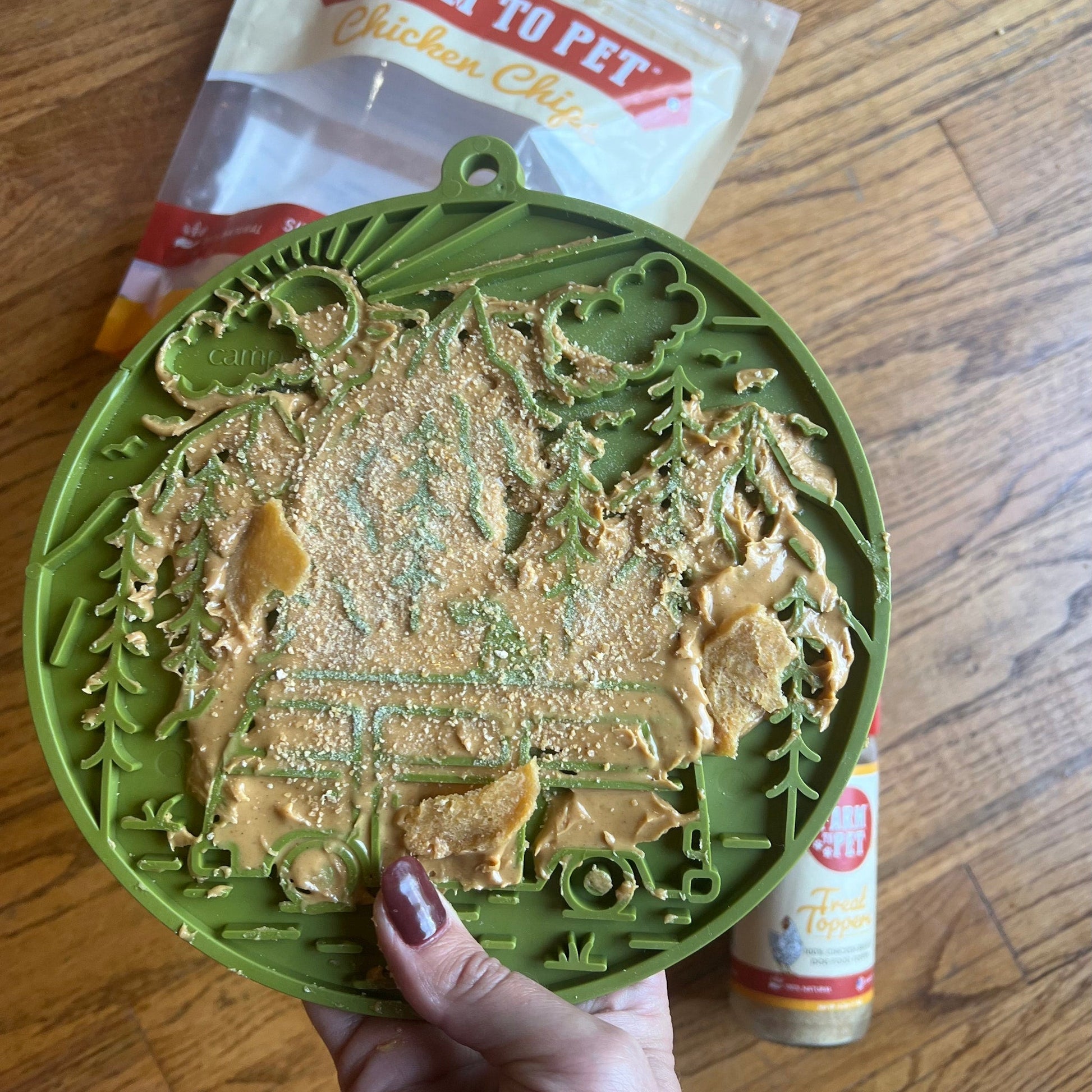 Green pet toy with peanut butter on a wooden surface
