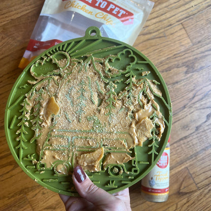 Green pet toy with peanut butter on a wooden surface