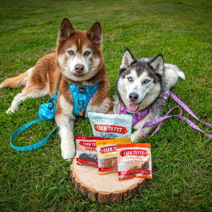 Two husky dogs with 'Farm to Pet' dog food packages on a grassy background