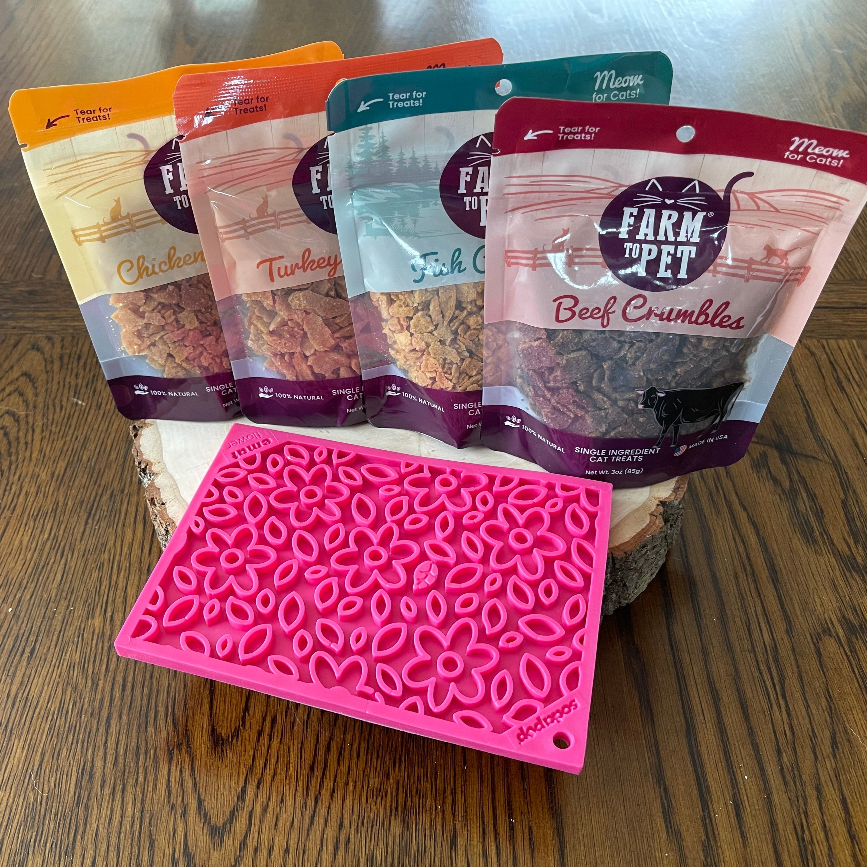 Five packages of Farm Pet treats on a wooden surface with a pink silicone mat.