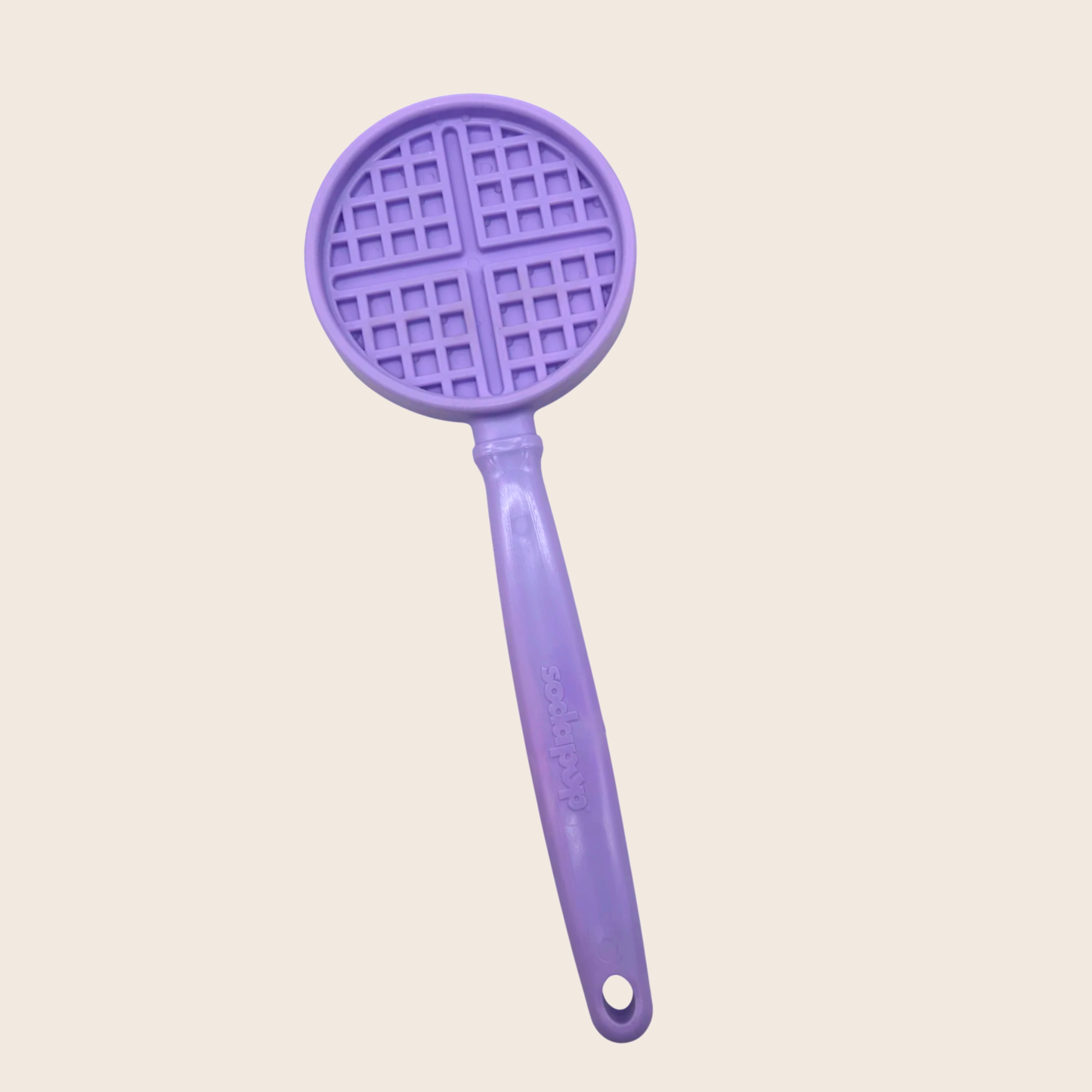 Purple kitchen tool with waffle-patterned top on a light beige background