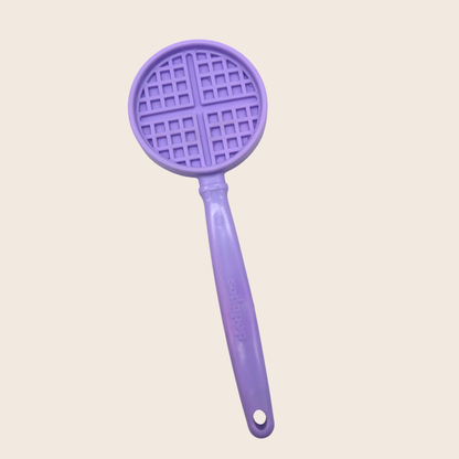 Purple kitchen tool with waffle-patterned top on a light beige background