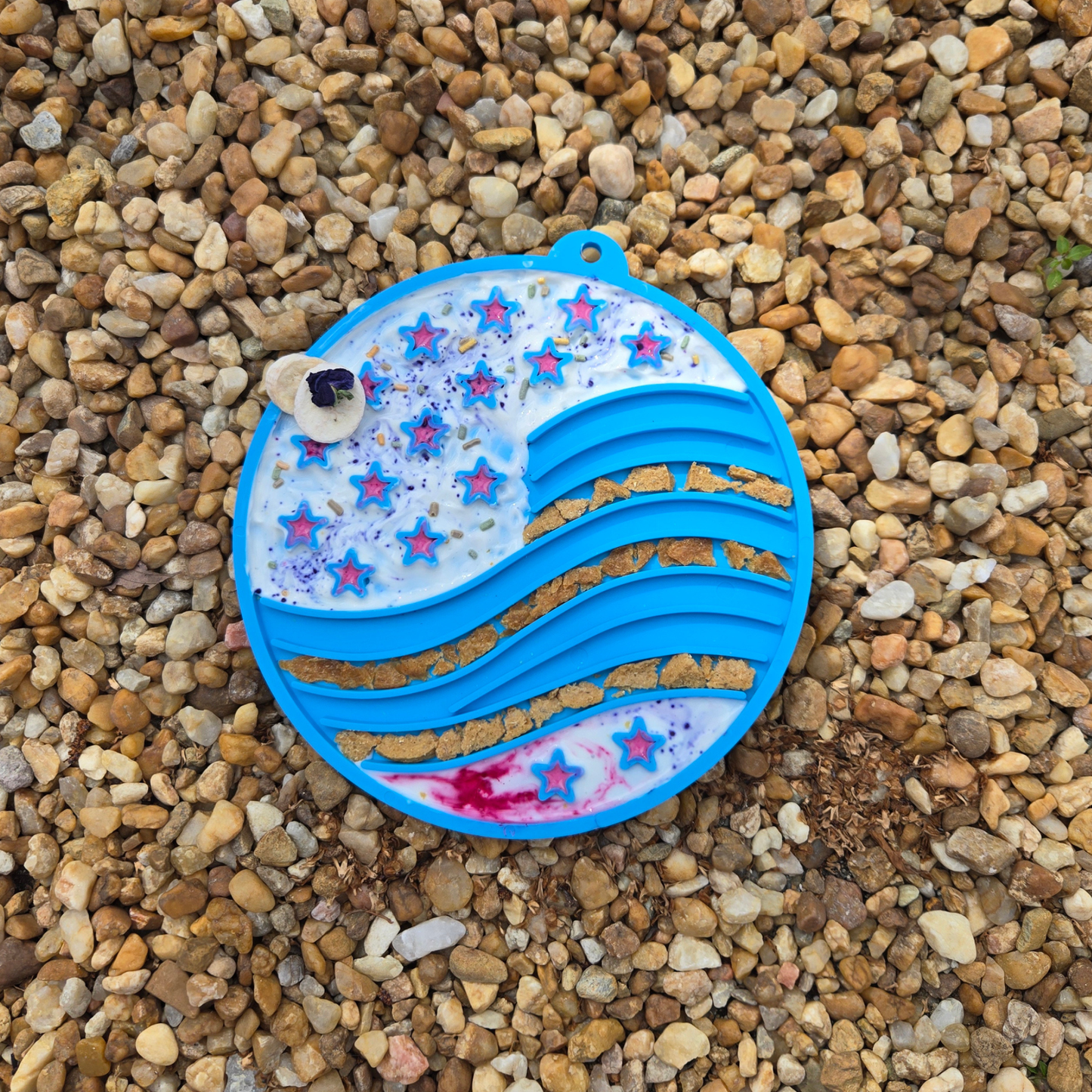 Colorful silicone sand timer on a pebbled surface