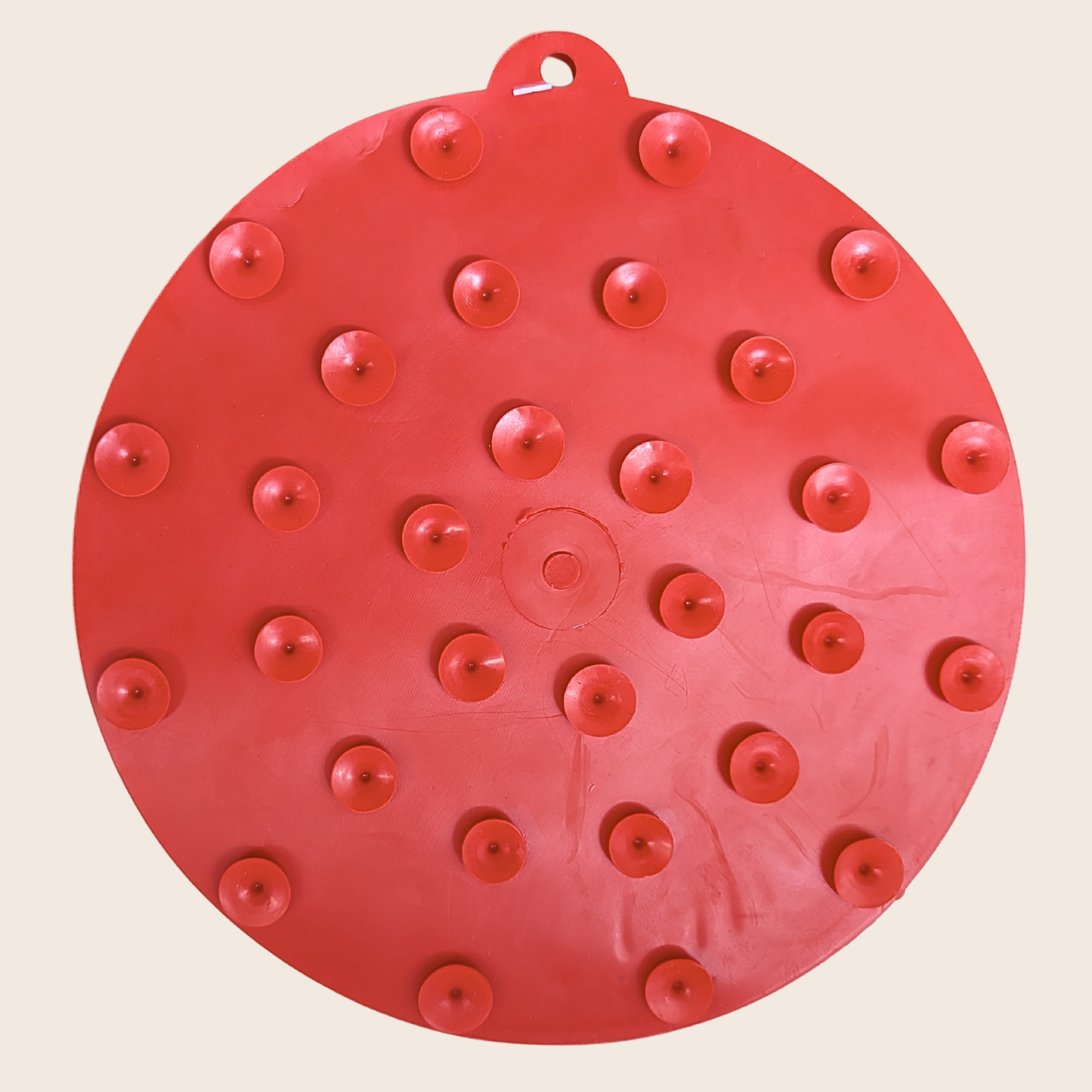 Red circular object with multiple small red protrusions on a beige background