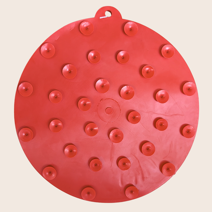 Red circular object with multiple small red protrusions on a beige background