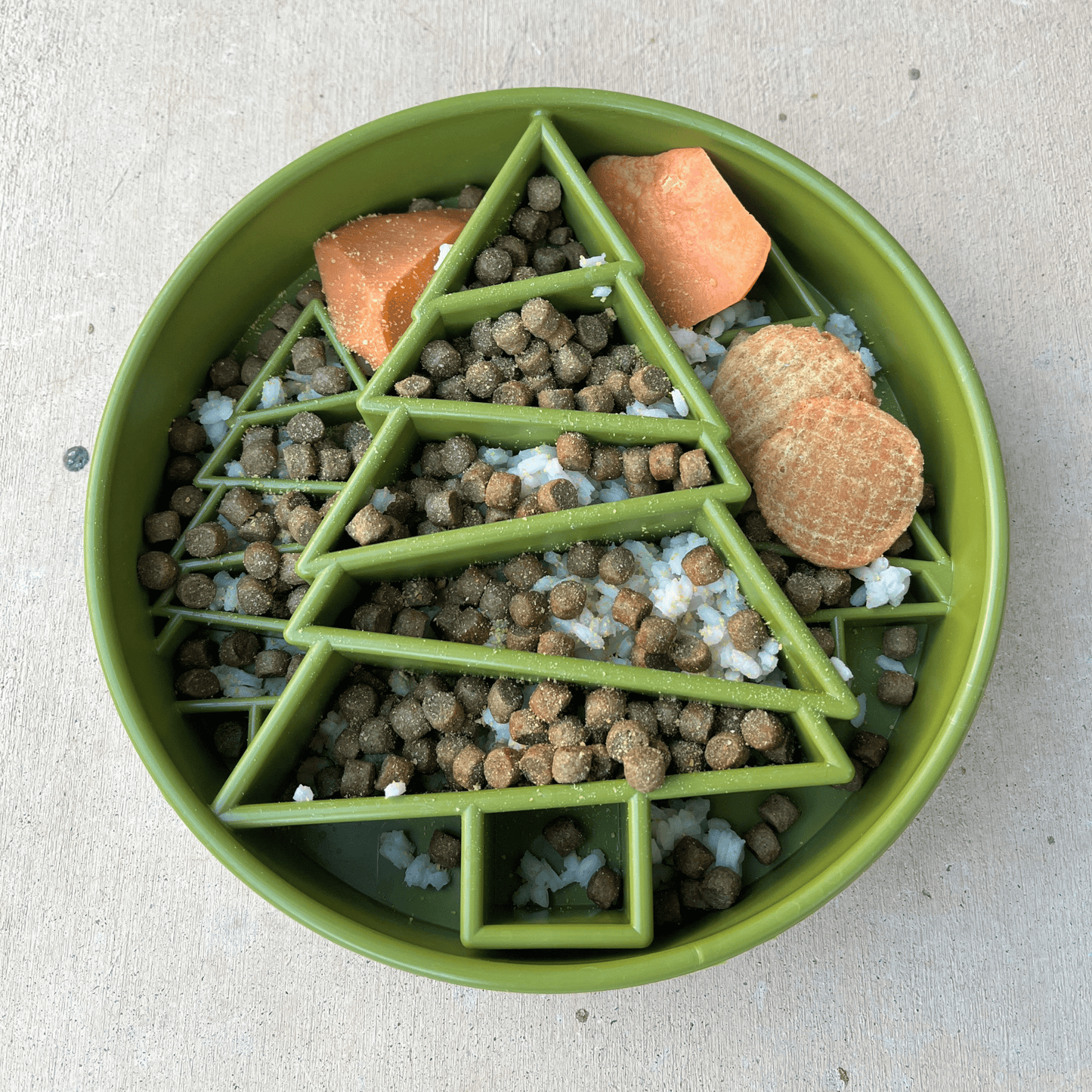 Green pet bowl with food shaped like a Christmas tree on a light background