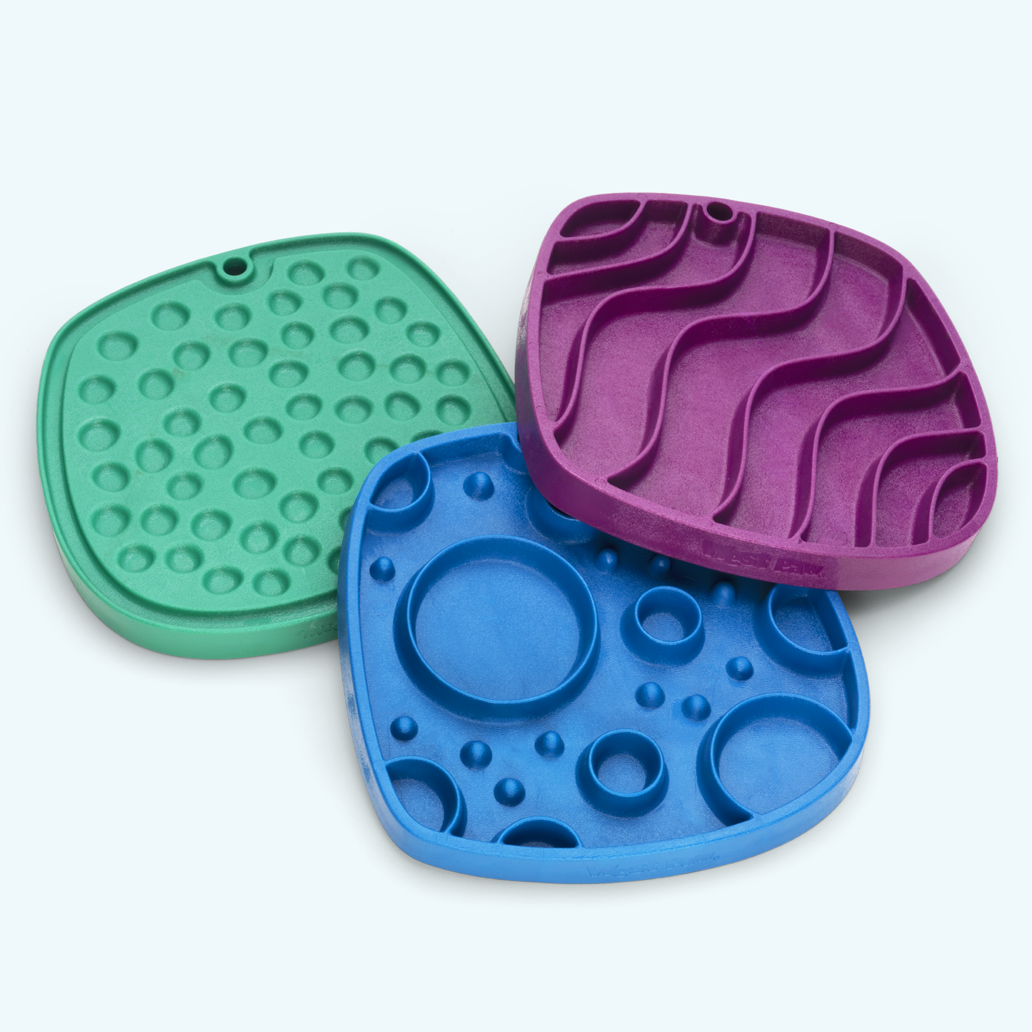 Three colorful silicone mats with different textures on a white background