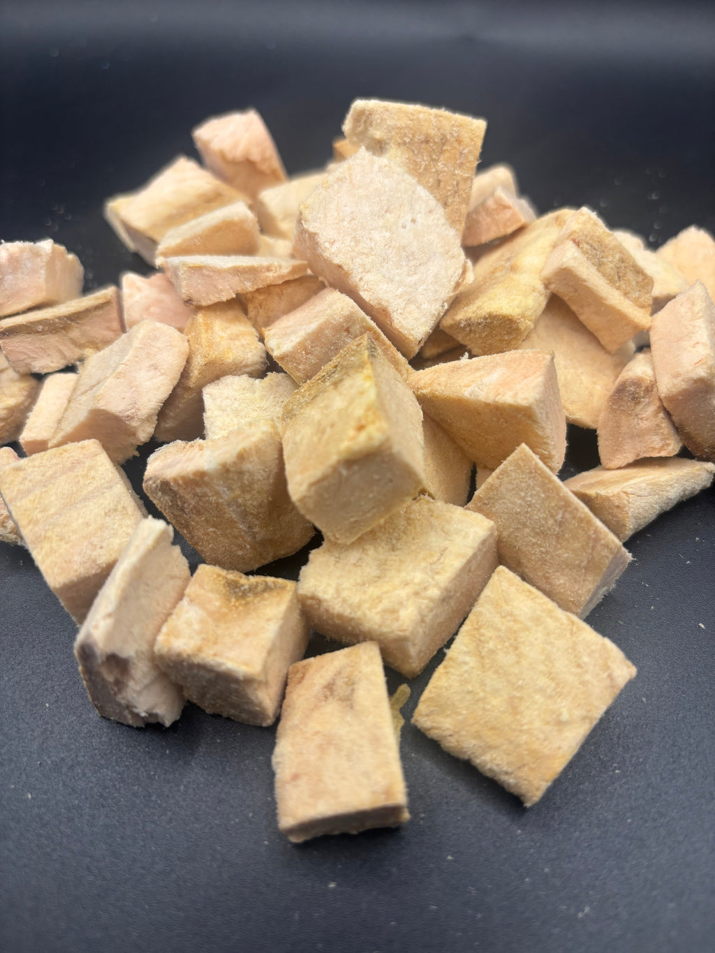 Cubed pieces of dried tofu on a dark surface
