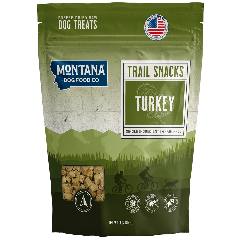 Green package of Montana Dog Food Co. trail snacks with turkey flavor on a white background