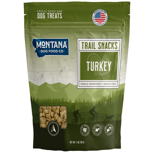 Green package of Montana Dog Food Co. trail snacks with turkey flavor on a white background