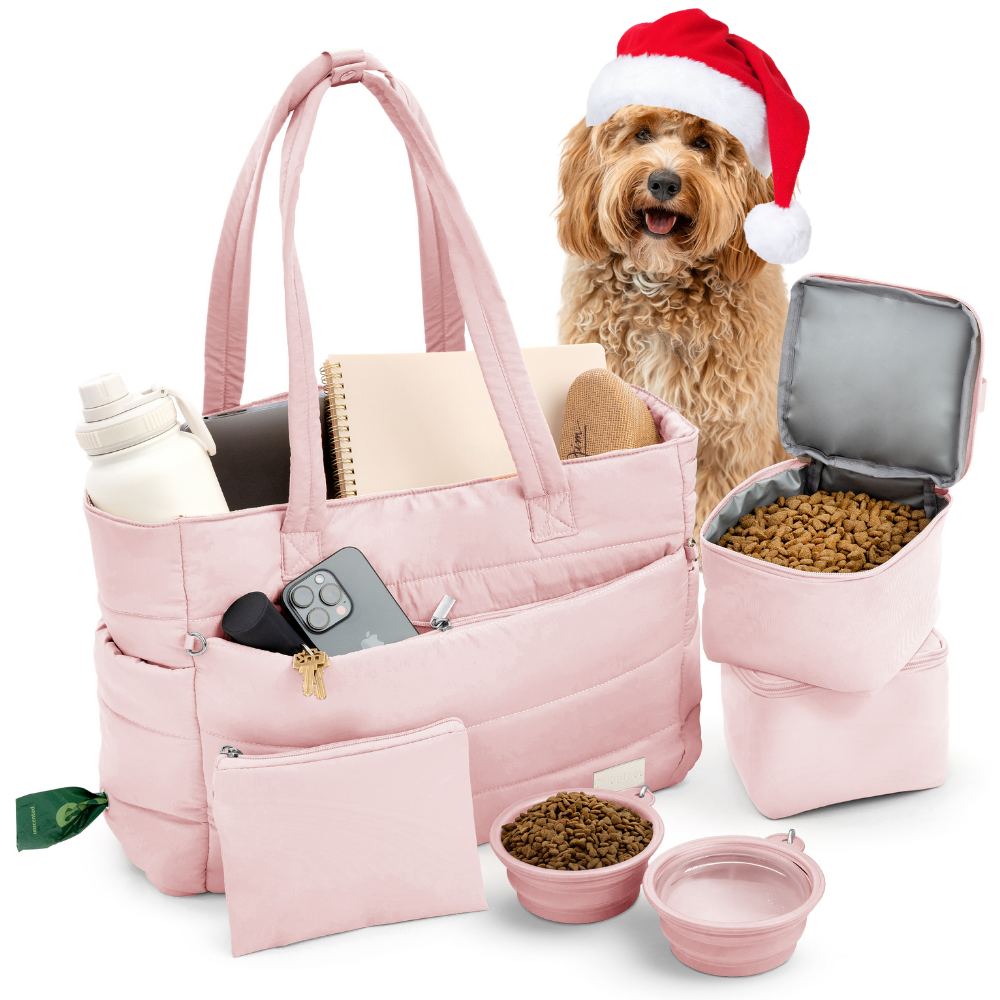 Pink pet travel bag with a dog wearing a Santa hat, food bowls, and treats on a white background.