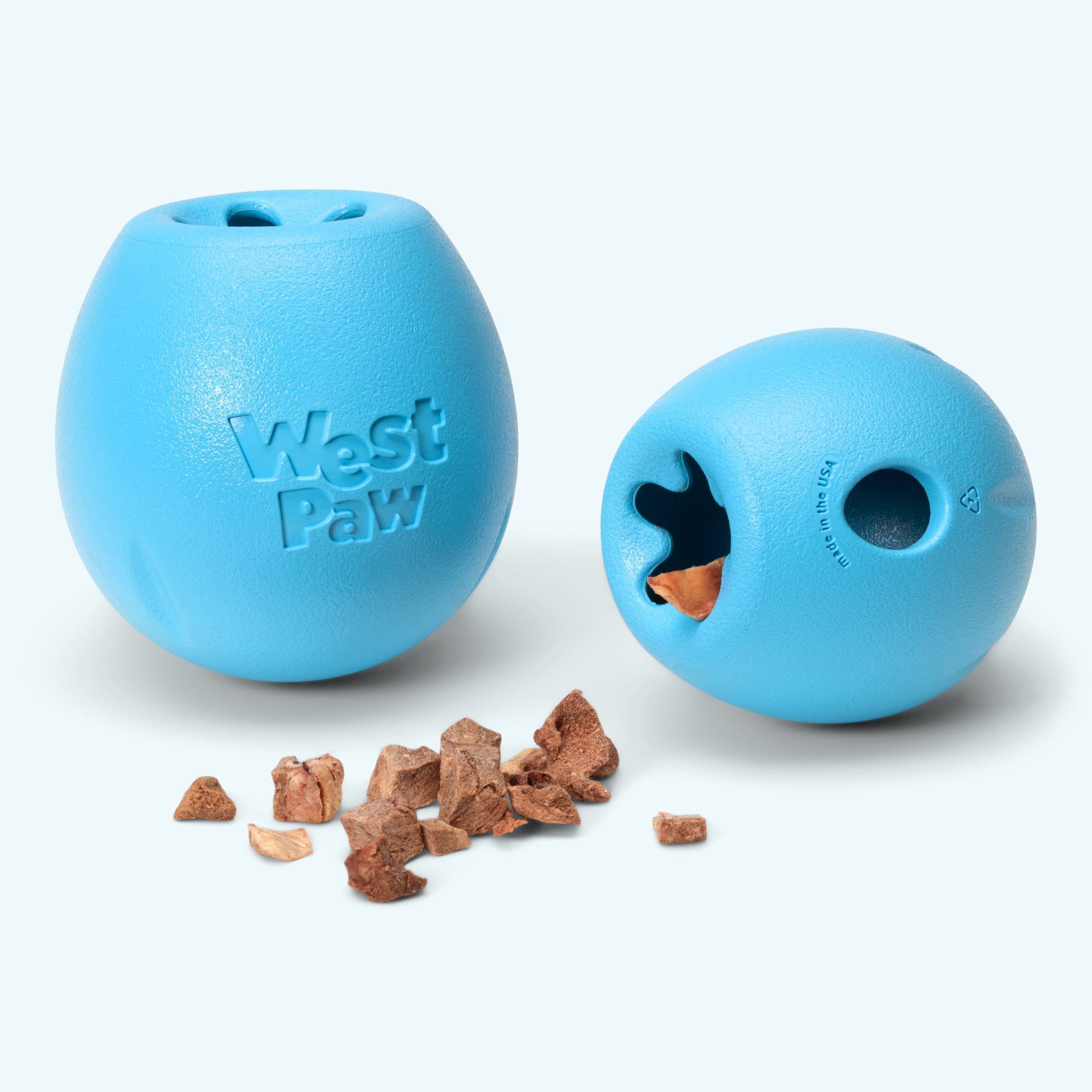 Two blue West Paw dog toys with treats on a white background