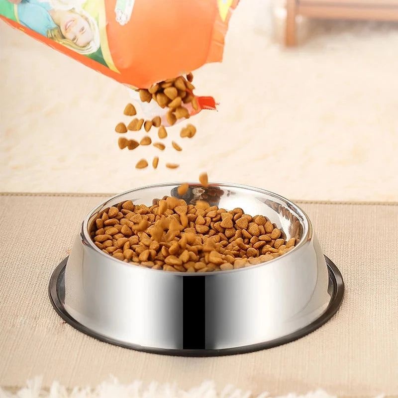 Dog food being poured into a metal bowl on a beige surface