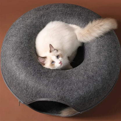Cat inside a gray donut-shaped pet bed on a brown background