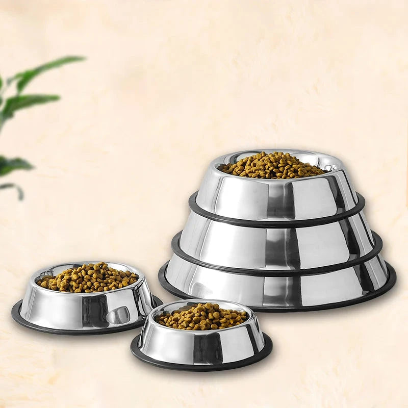 Set of three stainless steel pet bowls with food on a beige background