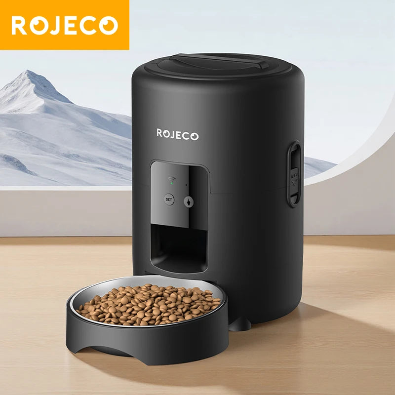 Black ROJECO pet feeder with a bowl of food on a wooden surface, mountainous background
