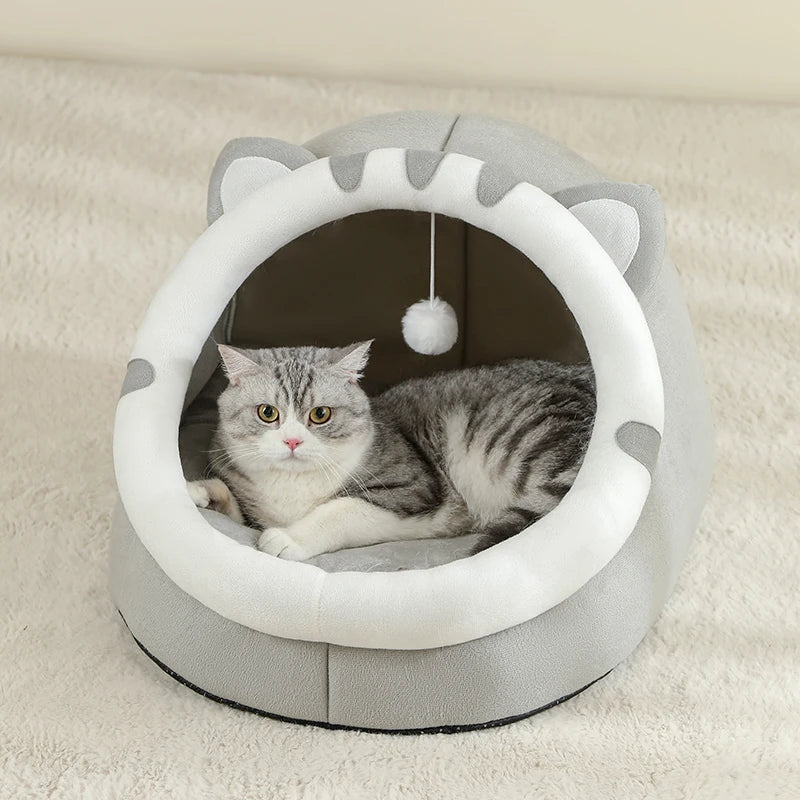 Cat lying inside a gray and white cat-shaped pet bed on a beige carpet.