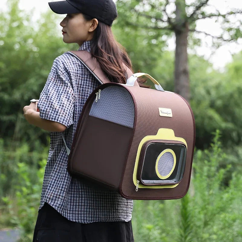 Person carrying a brown pet carrier with a yellow window outdoors