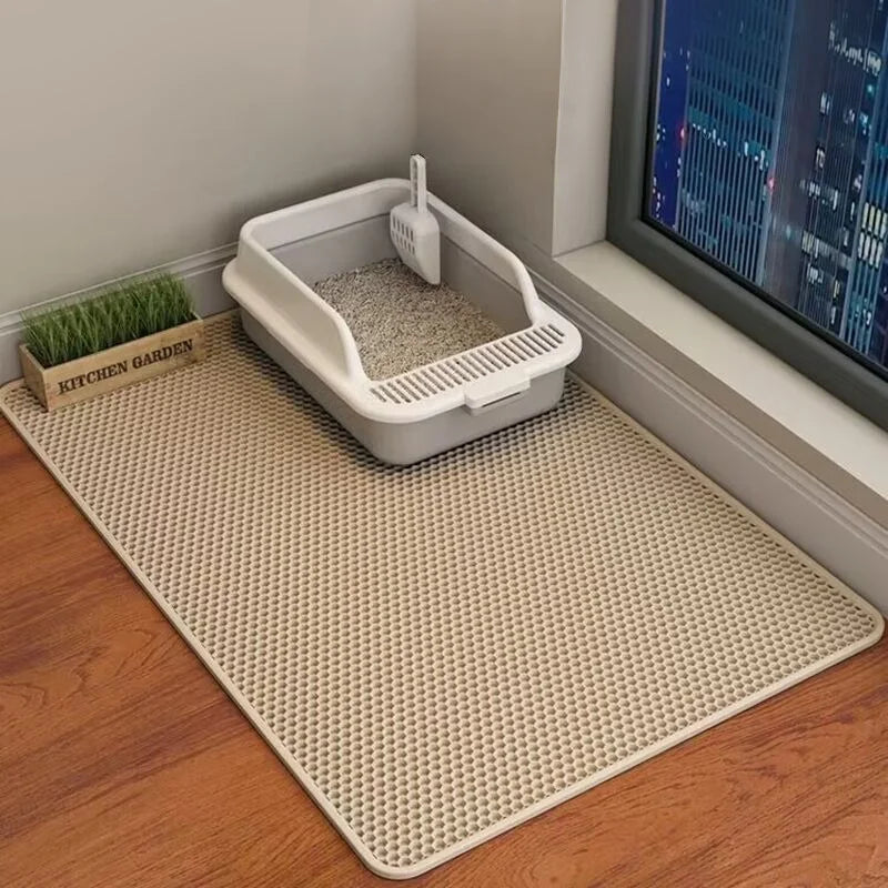 Cat litter box on a black mat with a view of a cityscape through a window.