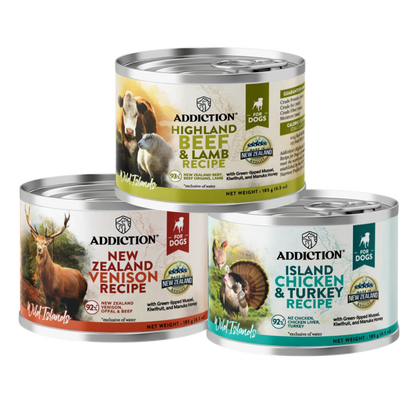 Three cans of Addiction dog food with different recipes on a white background