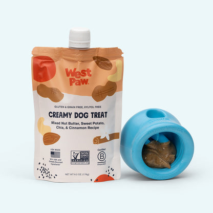 West Paw creamy dog treat package and blue dog toy on a white background